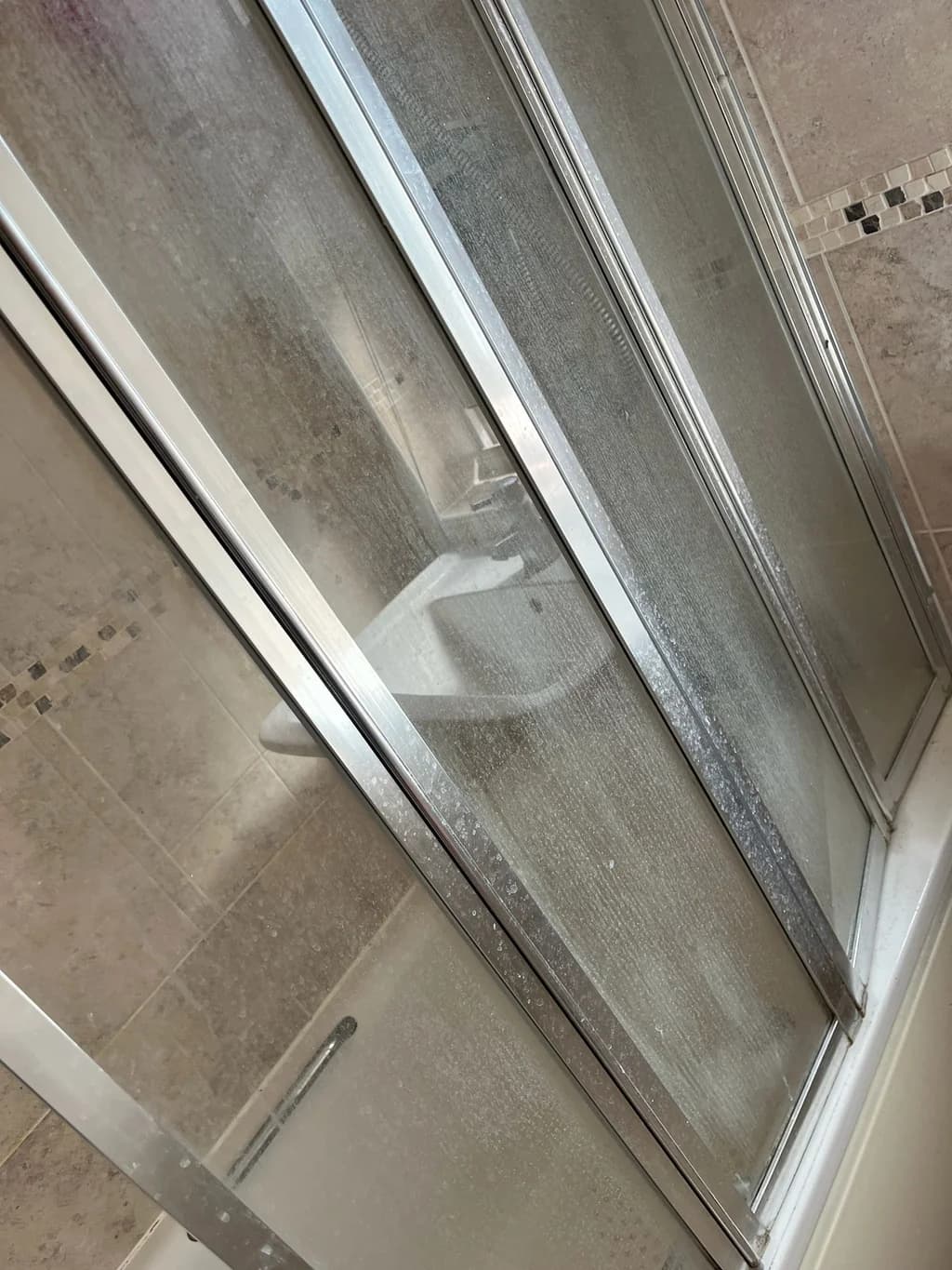 Bath shower doors coated in limescale before cleaning