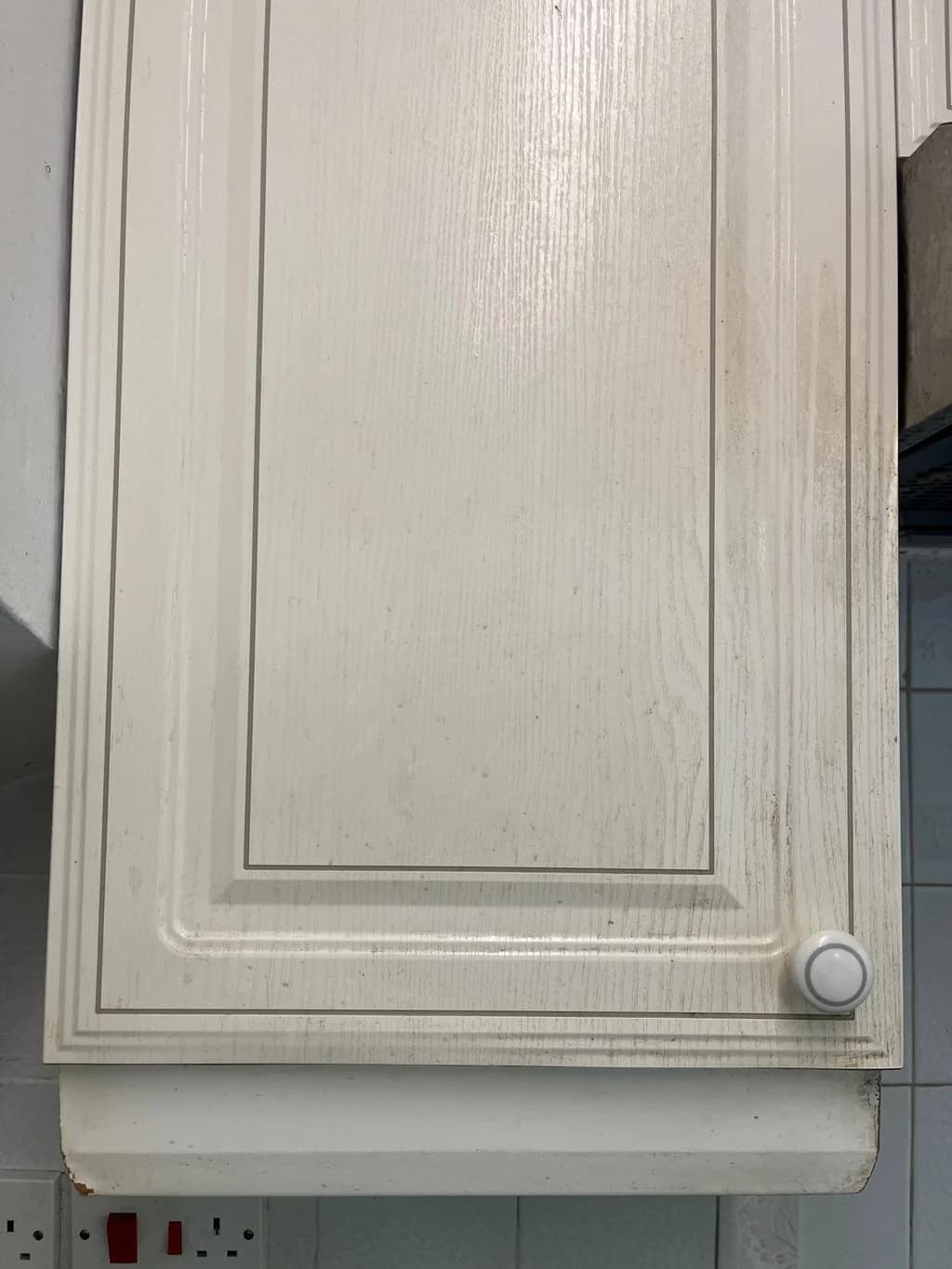 White kitchen cupboard door yellowed with grease before cleaning