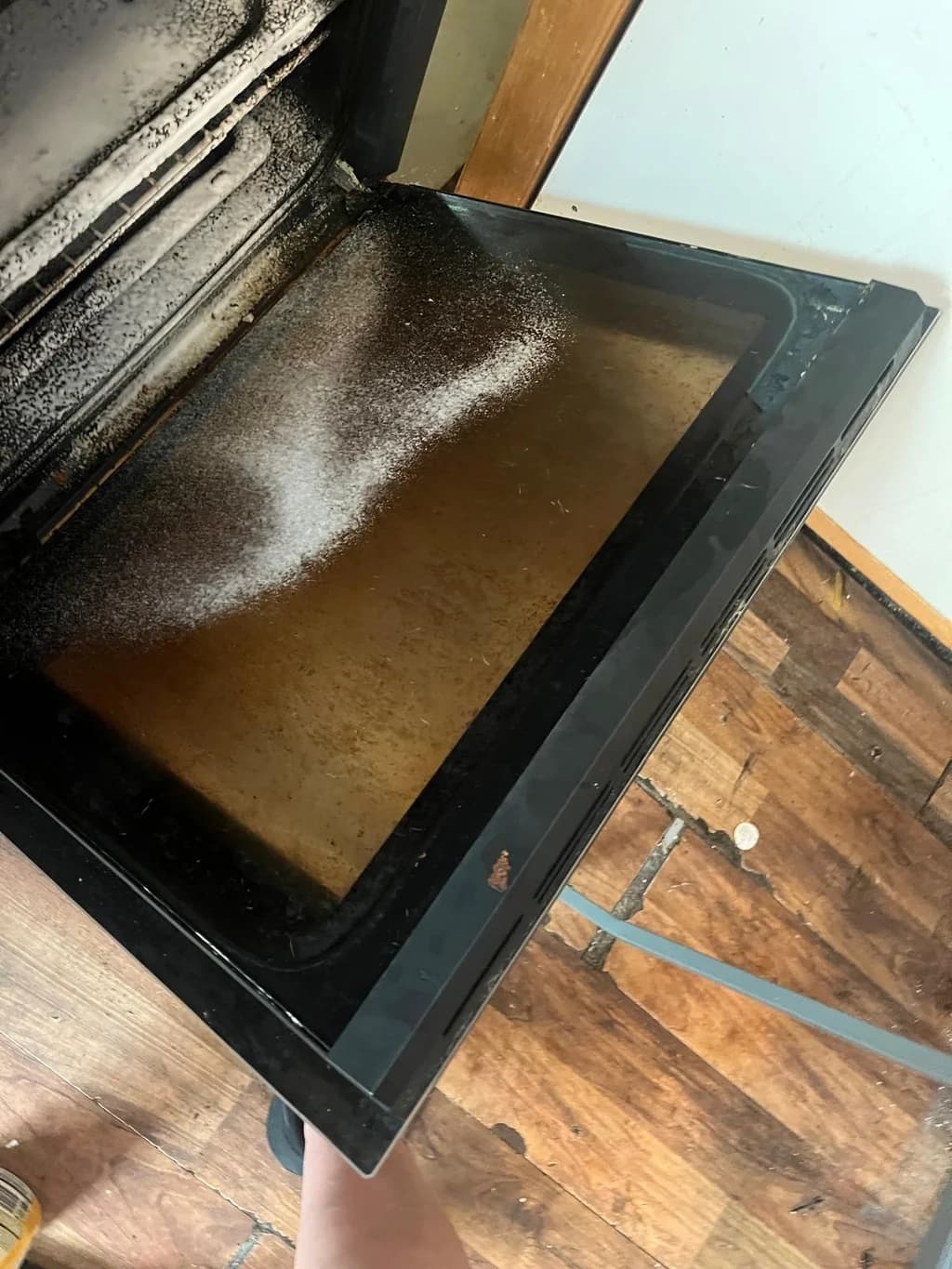 Oven door dulled by a greasy film before cleaning
